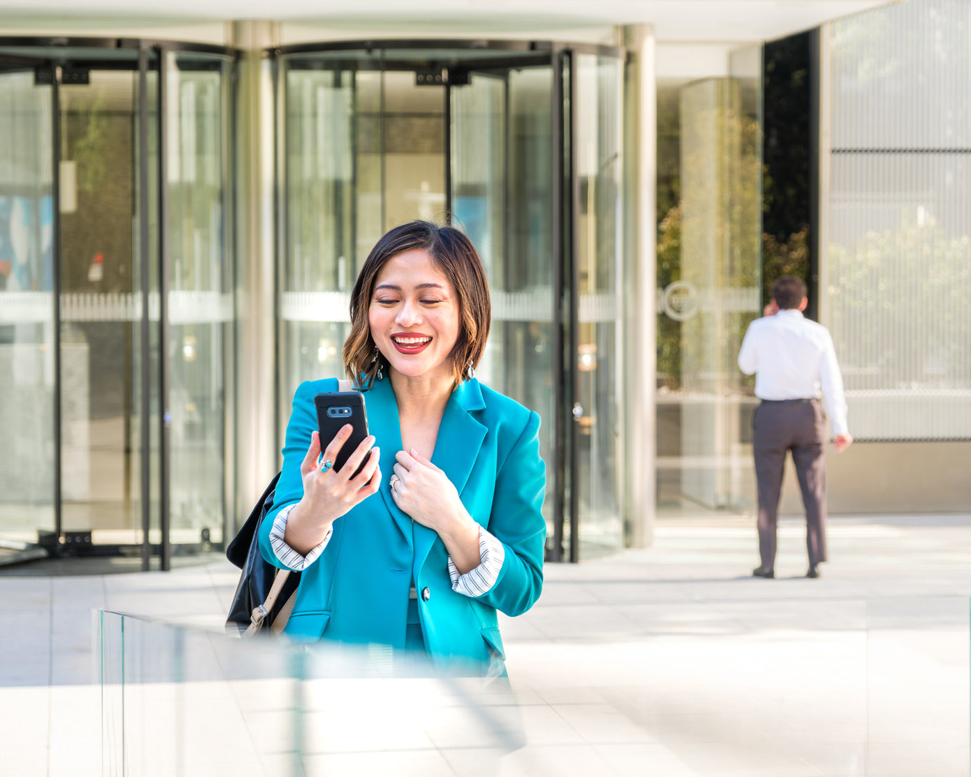Asian woman in blue suit smiling on a FaceTime call at a corporate office in Madrid